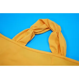 Close-up detail of yellow elegant slim-fit dress showing twisted gathered shoulder strap