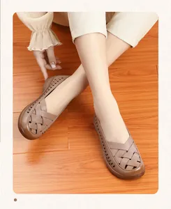 Sandales plates confortables en cuir marron ajouré pour femmes âgées sur sol en bois