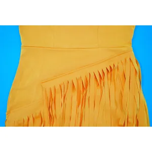 Close-up of elegant yellow slim dress with diagonal fringe detail on blue background