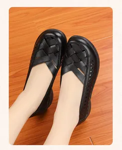 Gros plan sur des sandales plates en cuir souple noir tressé pour femmes âgées seniors.