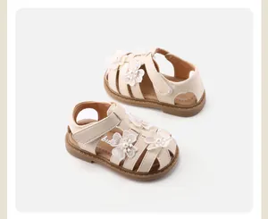 Vista dettagliata di sandali beige per neonata con fiori di pizzo e perle decorative.