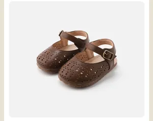 Détail montrant le motif ajouré et la bride à boucle sur les sandales marron bébé