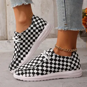 Nahaufnahme von stilvollen schwarz-weißen Canvas-Loafers mit Karomuster für Damen.