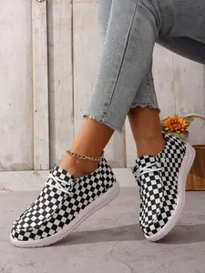 Detailansicht von lässigen schwarz-weiß karierten Slippern für Damen an einem Modell