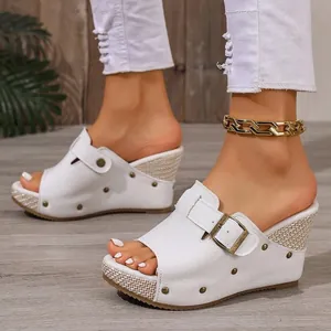 Detailed shot of white platform wedge sandals featuring metallic buckles and studs.