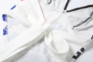 Close-up detail of white halter top featuring a tie-up bow and modern letter print