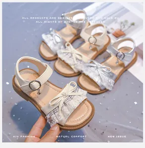 Close-up detail of lace bow and decorative charms on soft sole girls' princess sandals