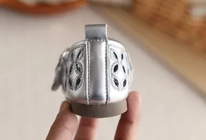 Détail macro du talon des sandales Mary Jane argentées évidées pour filles, style été chic