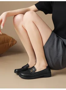 Close-up of black hollow leather loafers for women with a decorative gold flower buckle