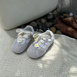 Detailed macro view of breathable white mesh toddler sneakers with cute daisy flower charms