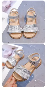 Detailed view of girls' silver metallic sandals with delicate lace bow and soft sole