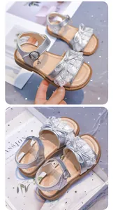 Detailed view of silver girls' sandals featuring delicate lace ruffles and bow