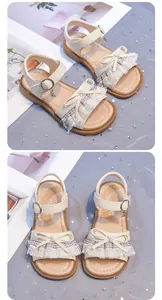 Detailed view of girls cream lace sandals with bow accents and star charms on soft sole