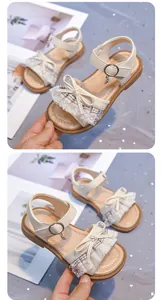 Close-up detail of beige girls lace princess sandals with bow and star charm