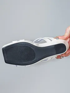 Gedetailleerd overzicht van de antislip zwarte zool van een witte sleehaksandaal.