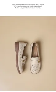 Close-up of beige leather loafers featuring intricate laser-cut floral patterns.