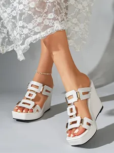Close-up van elegante witte plateauzolen met sleehak, H-bandjes en gouden accenten