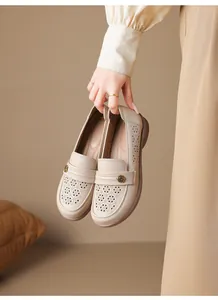 Close-up detail of beige breathable hollow-out loafers with elegant floral metallic buckle