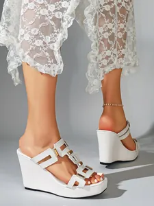 Detailweergave van witte sleehakmuiltjes met geometrische bandjes en plateau
