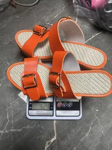 Foto dettagliata di sandali con zeppa arancioni su una bilancia che pesano 424 grammi