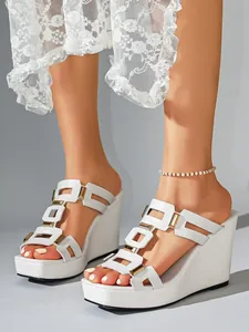 Macro detail van witte sleehak sandalen met gouden gespen en H-vormig bandje ontwerp