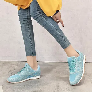 Vue détaillée de baskets en maille pailletée bleu clair avec d'épaisses semelles blanches.