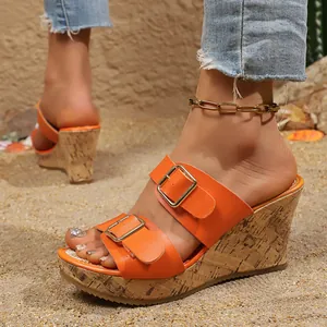 Dettaglio dei sandali con zeppa arancione con fibbie e suola platform effetto sughero