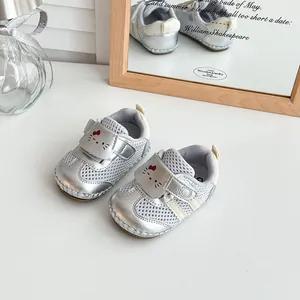 Macro shot of silver mesh baby pre-walker shoes with cute cat face and red bow detail