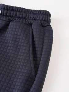 Close-up detail of navy men's sports shorts featuring unique quilted square texture.