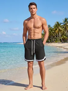Detail view of men's black checkered sports shorts with white drawstring on a tropical beach