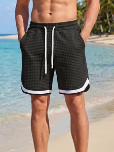 Close-up of men's black grid-textured sports shorts with white drawstring details
