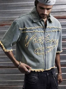 Détail d'une chemise en jean bleu délavé pour hommes avec fermeture éclair et franges
