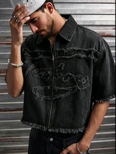 Détail d'une chemise en jean noir pour homme avec fermeture éclair et pompons effilochés