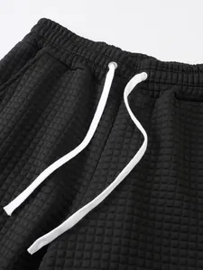 Detailed macro view of black waffle texture men's sports shorts with white drawstring.