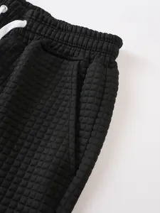 Close-up of black men's sports shorts featuring checkered waffle texture and side pocket detail
