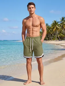 Close-up of men's olive green grid texture shorts on a beach model
