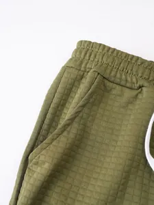 Close-up of olive green men's waffle knit shorts showing fabric texture and pocket detail.