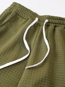 Close-up of olive green waffle knit men's shorts with white drawstring waistband