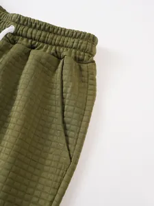 Close-up of olive green men's sports shorts with waffle texture and elastic drawstring waist