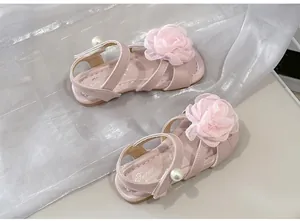 Primo piano di sandali rosa per bambine con grandi fiori di stoffa e perle decorative