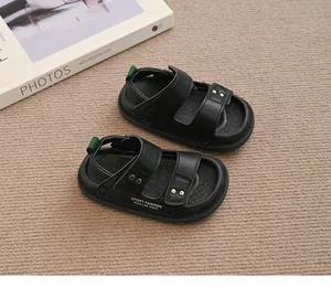 Nahaufnahme schwarzer Kinder-Sandalen mit offener Zehenpartie und weißer Schrift