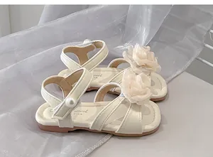 Dettaglio di eleganti sandali a fiori color crema per bambine con suole morbide e perle.