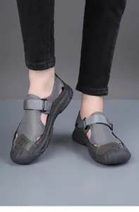 Close-up view of grey breathable mesh outdoor sandals for men on feet in a studio setting