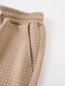 Detail of men's sports shorts featuring elastic waistband and grid quilted fabric texture