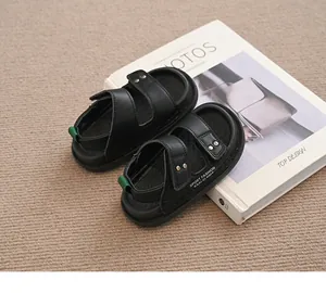 Nahaufnahme schwarzer Kindersandalen mit Doppelriemen und grüner Fersenschlaufe