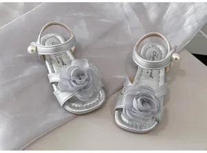 Primo piano di sandali argento da bambina con elegante rosa in tessuto e perle