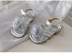 Primo piano di sandali argento da bambina con fiore in tessuto grigio e perla