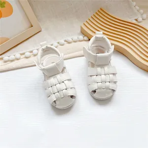 Nahaufnahme der weißen Baby-Sandalen mit gewebten Riemen und praktischem Klettverschluss