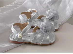 Dettaglio di sandali argentati da bambina con fiori di stoffa e perla.