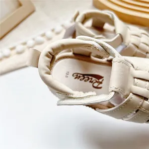 Nahaufnahme der cremefarbenen Baby-Ledersandalen mit weichem Fersenbereich und Preen-Logo